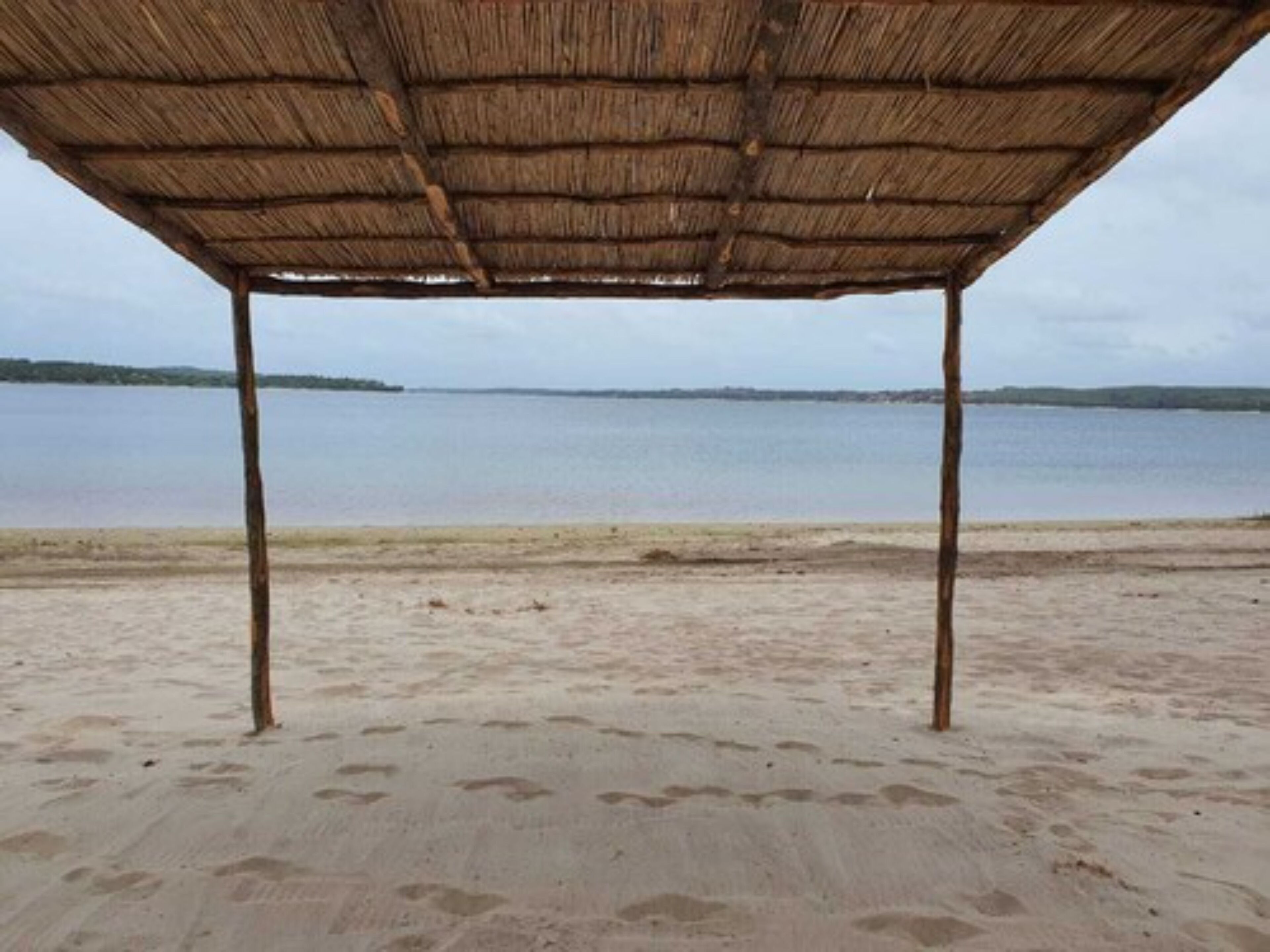 A beach with a thatched roof structure.