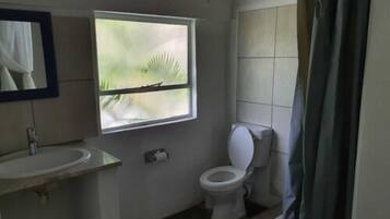 Bagno con lavandino, WC e finestra vista palme.