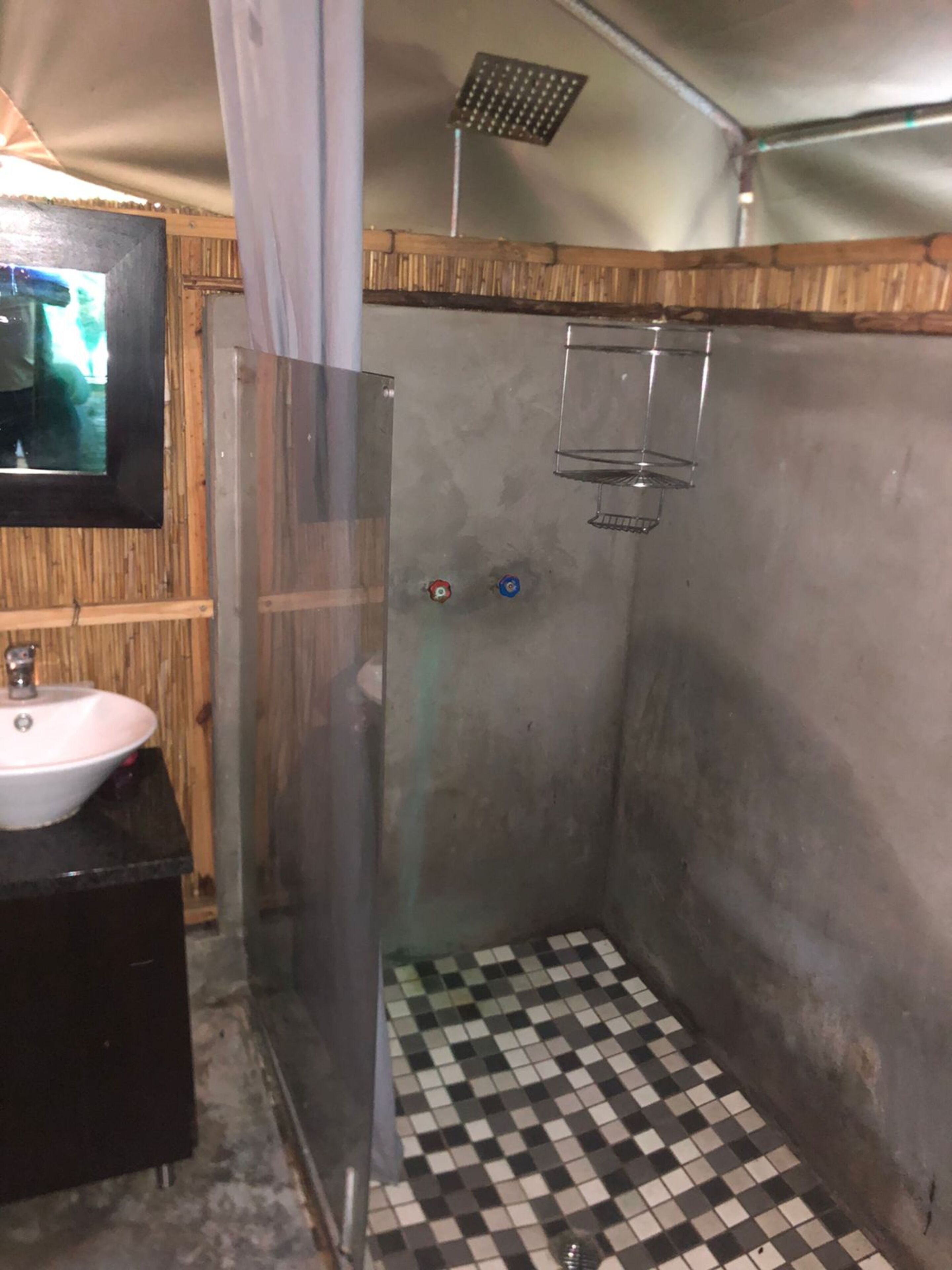 A bathroom with a checkered floor, a sink, and a shower enclosure.