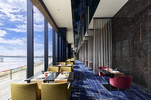 Enjoy meals with a river view from this dining area featuring a long table and comfortable seating.
