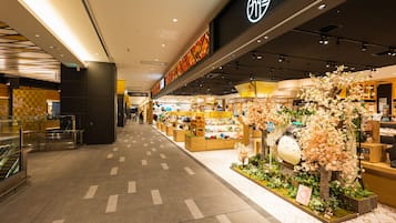 A shopping mall corridor with a store featuring a large floral display and a sign with Japanese characters.