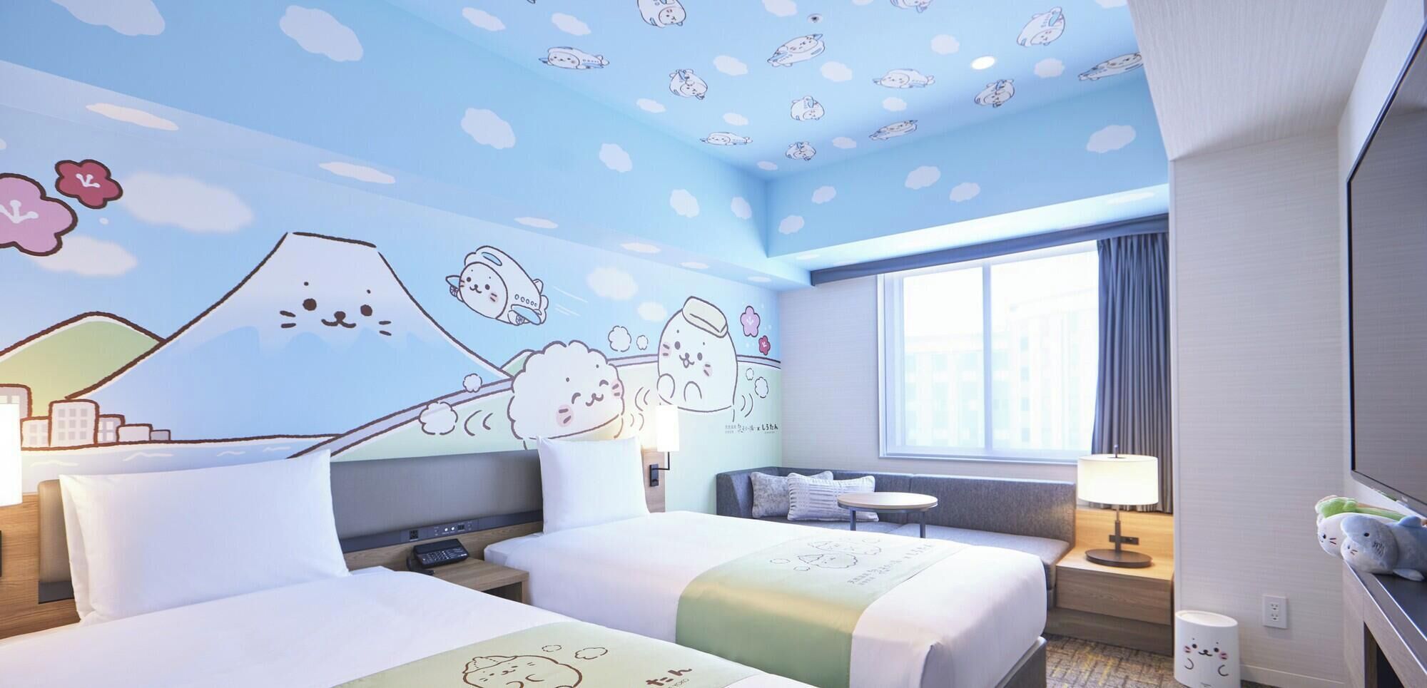 Hotellihuone, jossa on kaksi sänkyä, työpöytä, tuoli, televisio ja ikkuna.