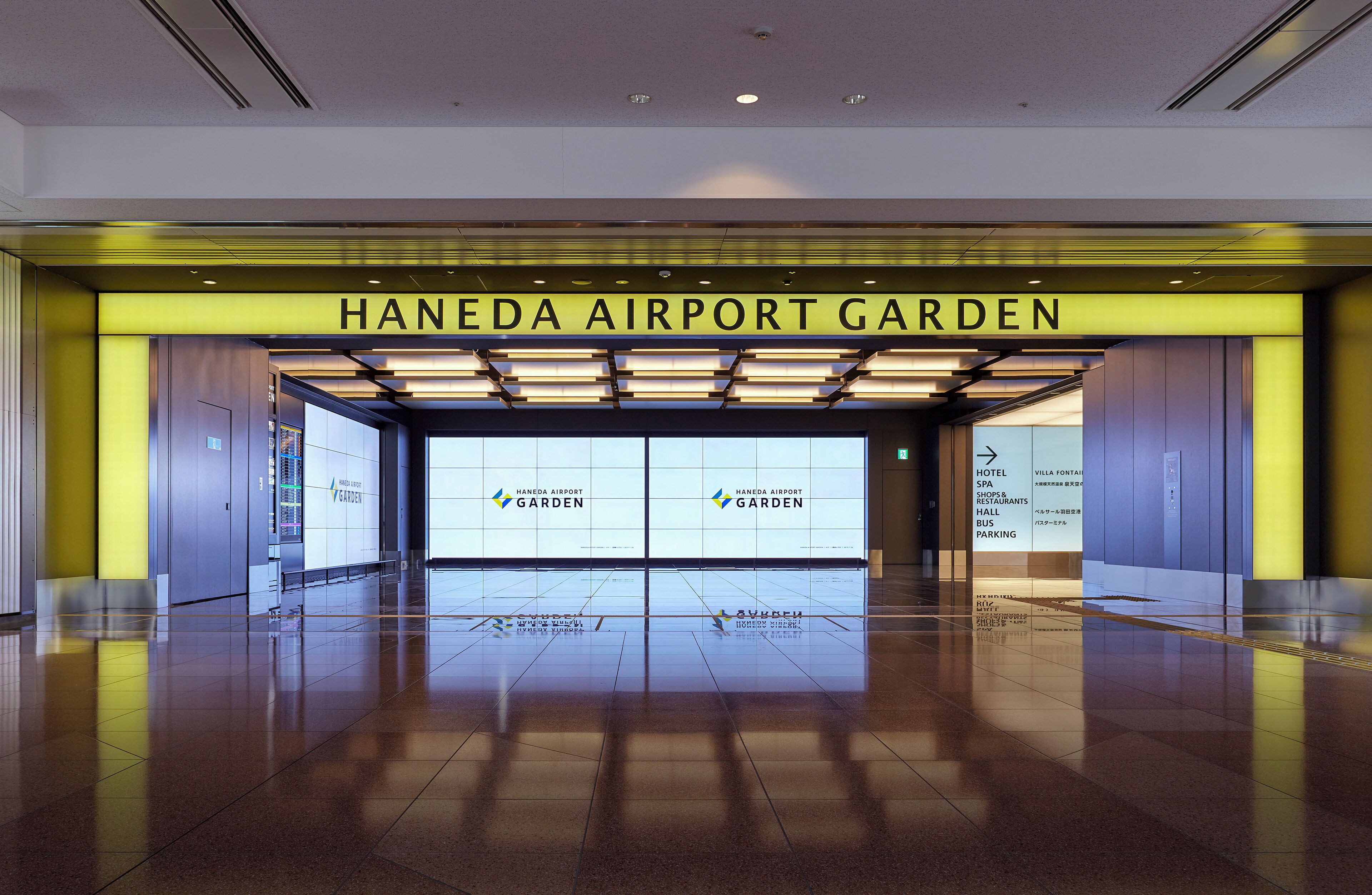 The entrance to Haneda Airport Garden with clear signage for the hotel, spa, shops, restaurants, and bus parking.