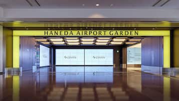 The entrance to Haneda Airport Garden with clear signage for the hotel, spa, shops, restaurants, and bus parking.