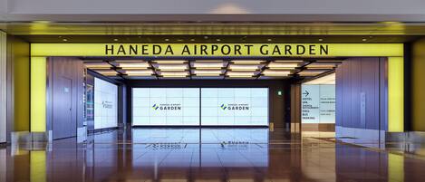The entrance to Haneda Airport Garden with clear signage for the hotel, spa, shops, restaurants, and bus parking.