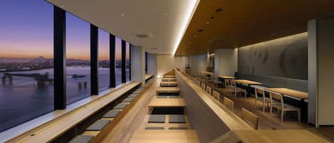 A modern interior with tiered seating and large windows offering a city view.
