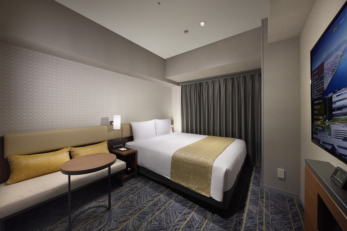 Ein Hotelzimmer mit Bett, Sofa, einem kleinen Tisch und Fernseher.