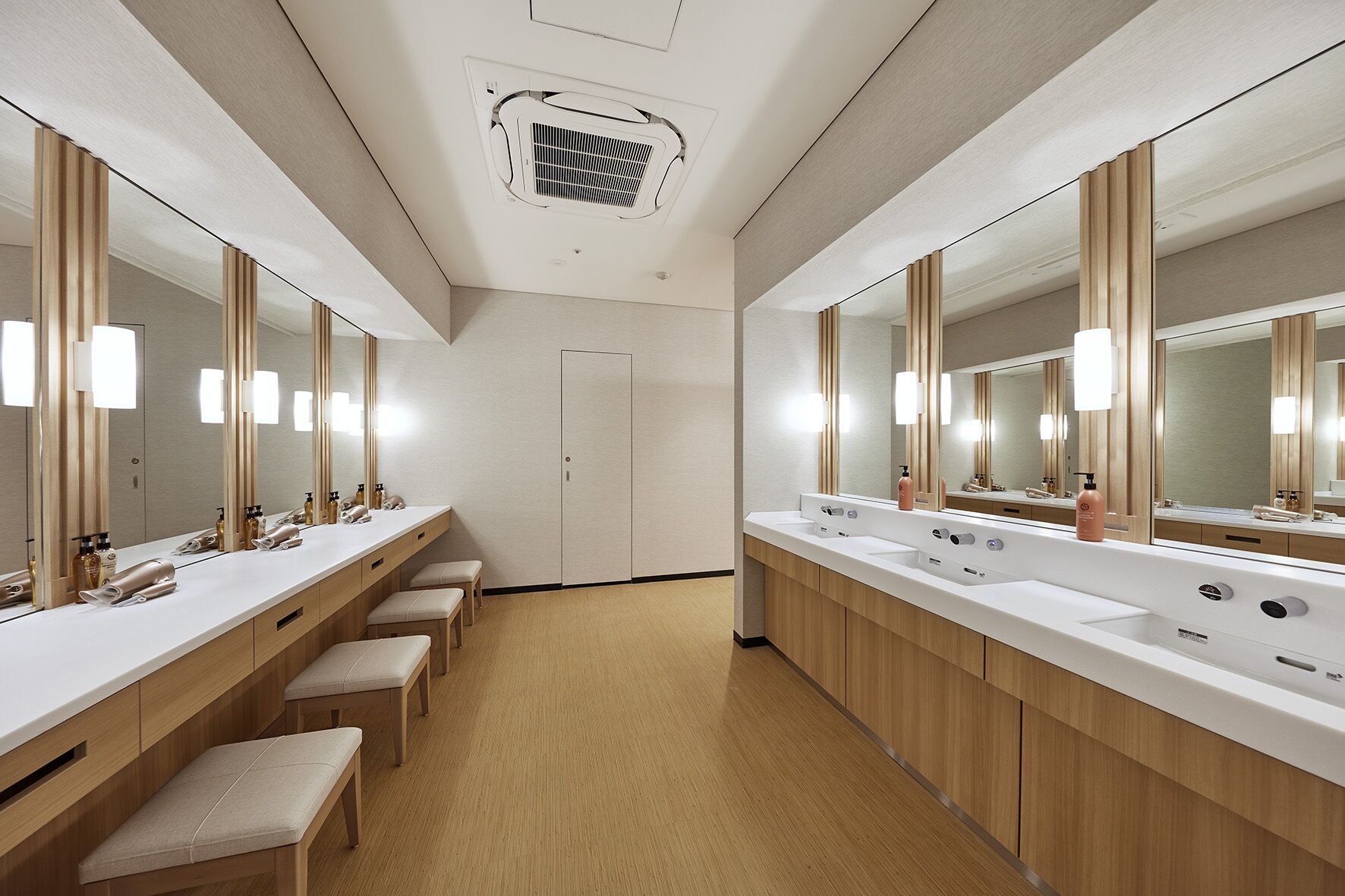 A modern bathroom with two sinks, large mirrors, and wooden benches.