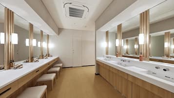 A modern bathroom with two sinks, large mirrors, and wooden benches.
