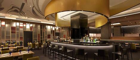A modern restaurant with a bar area, seating arrangements, and a decorative ceiling.