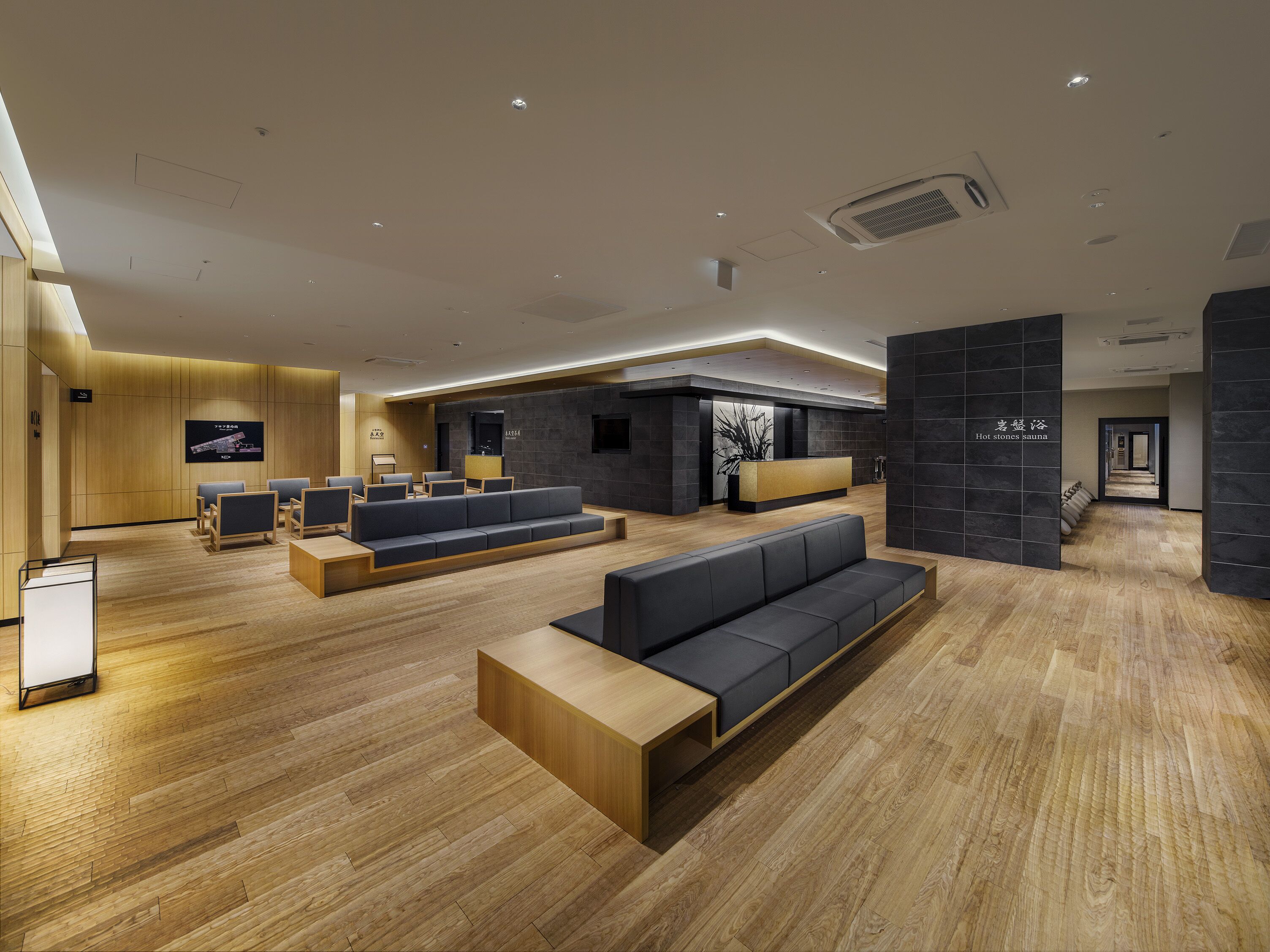 A modern lobby with wooden flooring, a reception desk, seating areas, and a spa section.