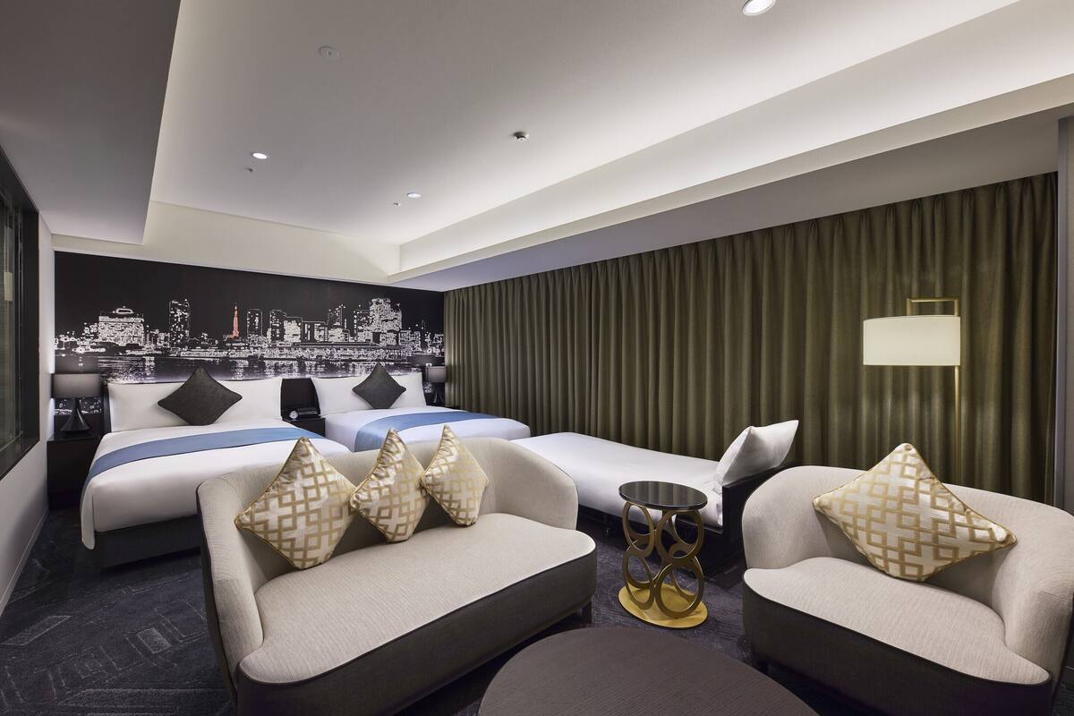 Ein modernes Hotelzimmer mit Stadtbild-Wandgemälde, zwei Betten, einer Couch, einem kleinen Tisch und einer Stehlampe.