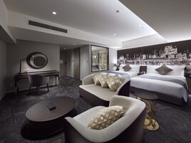 Ein modernes Hotelzimmer mit einem großen Bett, einer Sitzecke, einem Schreibtisch und einem runden Spiegel.