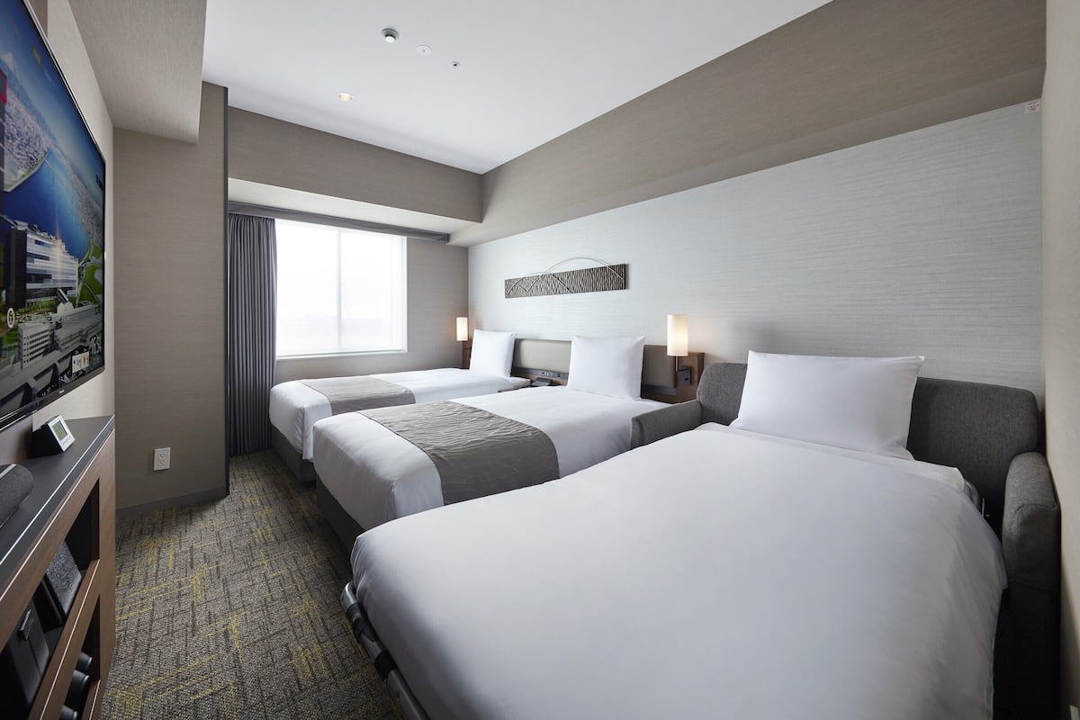 Ein Hotelzimmer mit zwei Betten, einem Fernseher und einem Schreibtisch.