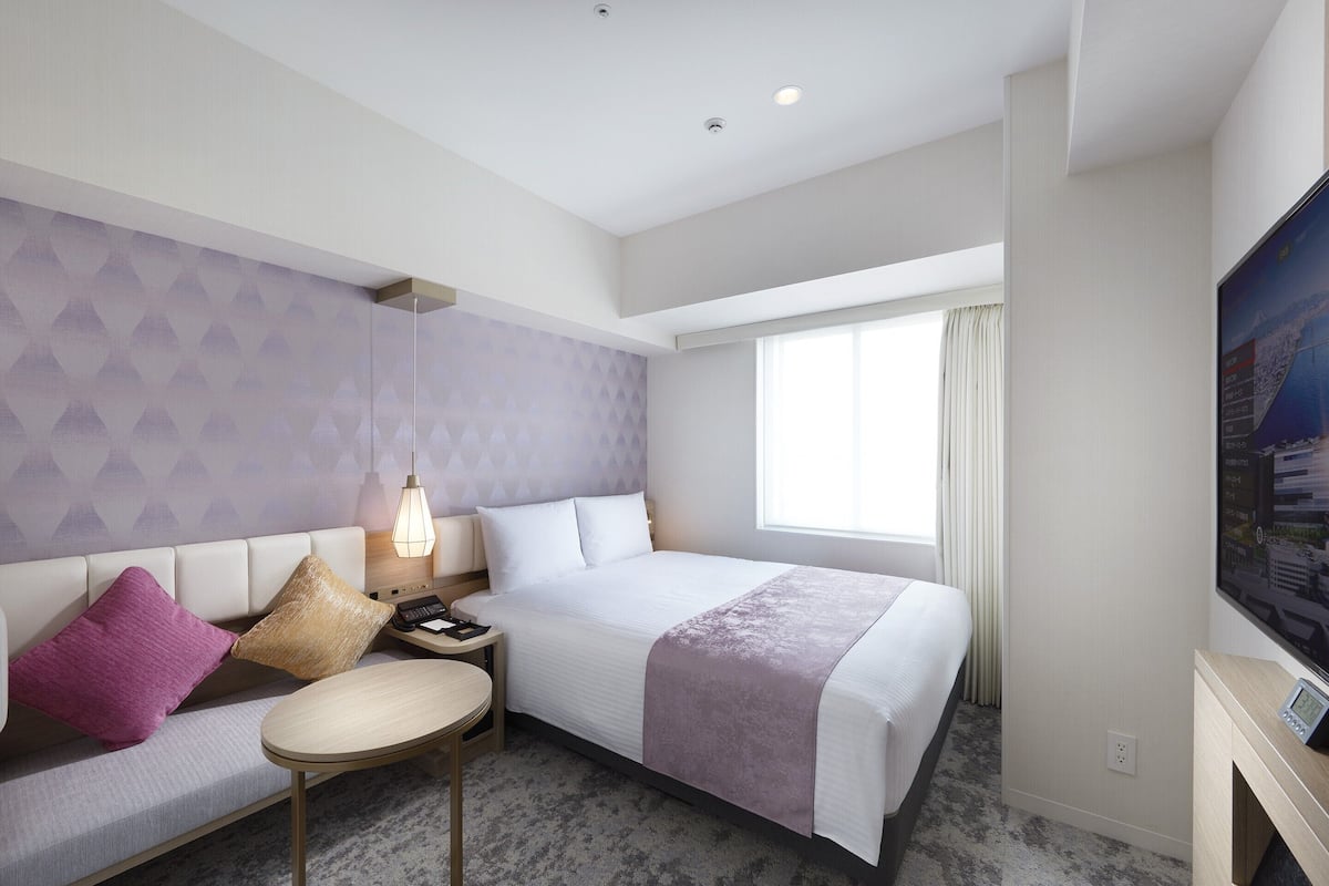 Ein Hotelzimmer mit Bett, Sofa, kleinem Tisch und Fernseher.