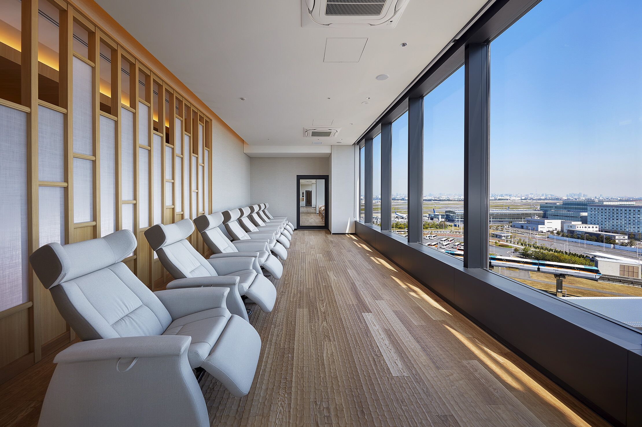 A row of white chairs with a view of a cityscape through large windows.