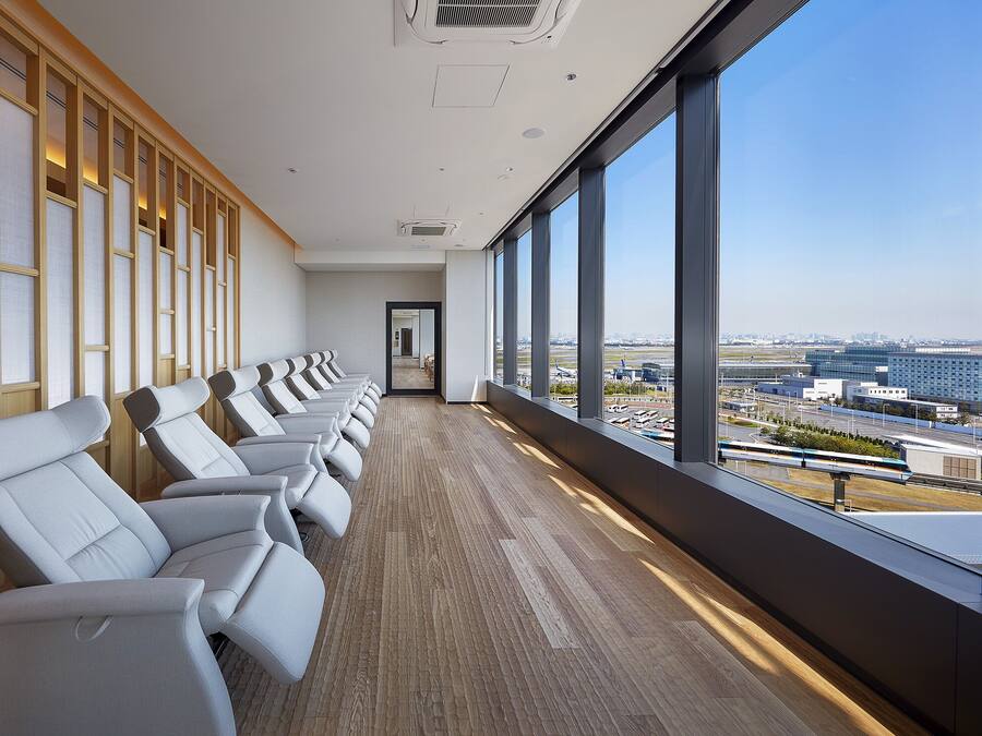 A row of white chairs with a view of a cityscape through large windows.