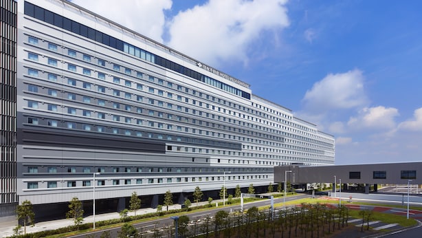 Ein modernes Hotelgebäude mit mehreren Stockwerken, großen Fenstern und einem flachen Dach.