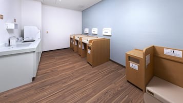 A restroom with a sink, three toilets, and a trash bin.