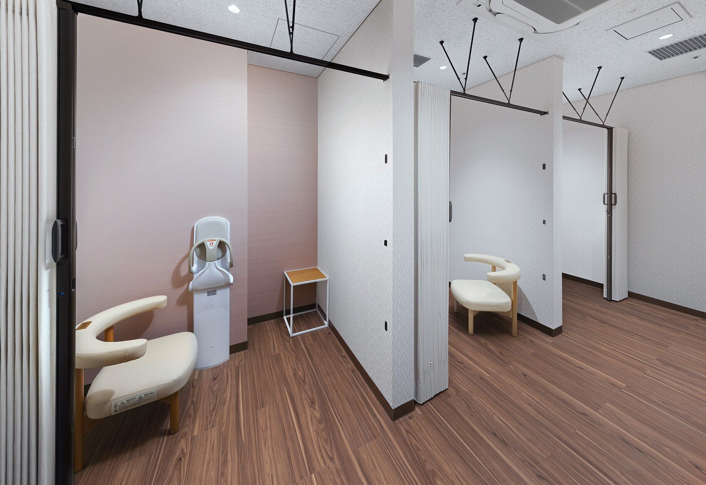 Una habitación moderna y luminosa con suelo de madera, mostrador de recepción y zona de estar con una silla y una pequeña mesa.