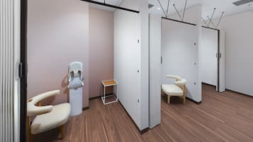 Una habitación moderna y luminosa con suelo de madera, mostrador de recepción y zona de estar con una silla y una pequeña mesa.