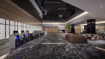 A spacious lobby with a marble floor, a reception desk, seating area, and a large windowed wall.