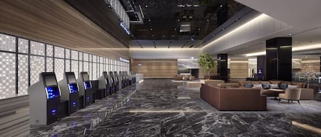 A spacious lobby with a marble floor, a reception desk, seating area, and a large windowed wall.