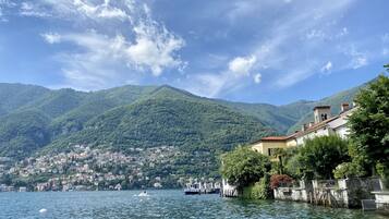 A lakeside view with a mountain backdrop, a dock, and a building with a red roof.