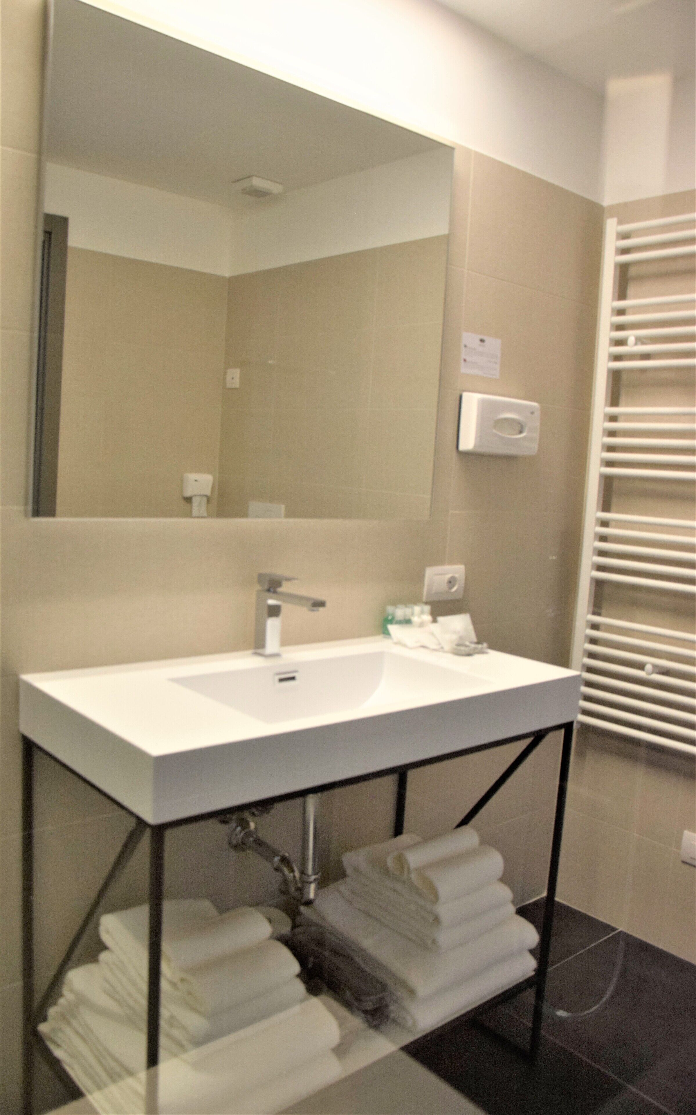 A bathroom with a white sink, a mirror, and a towel rack.