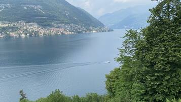 A lake with a boat creating a wake, surrounded by lush green hills and a small town.