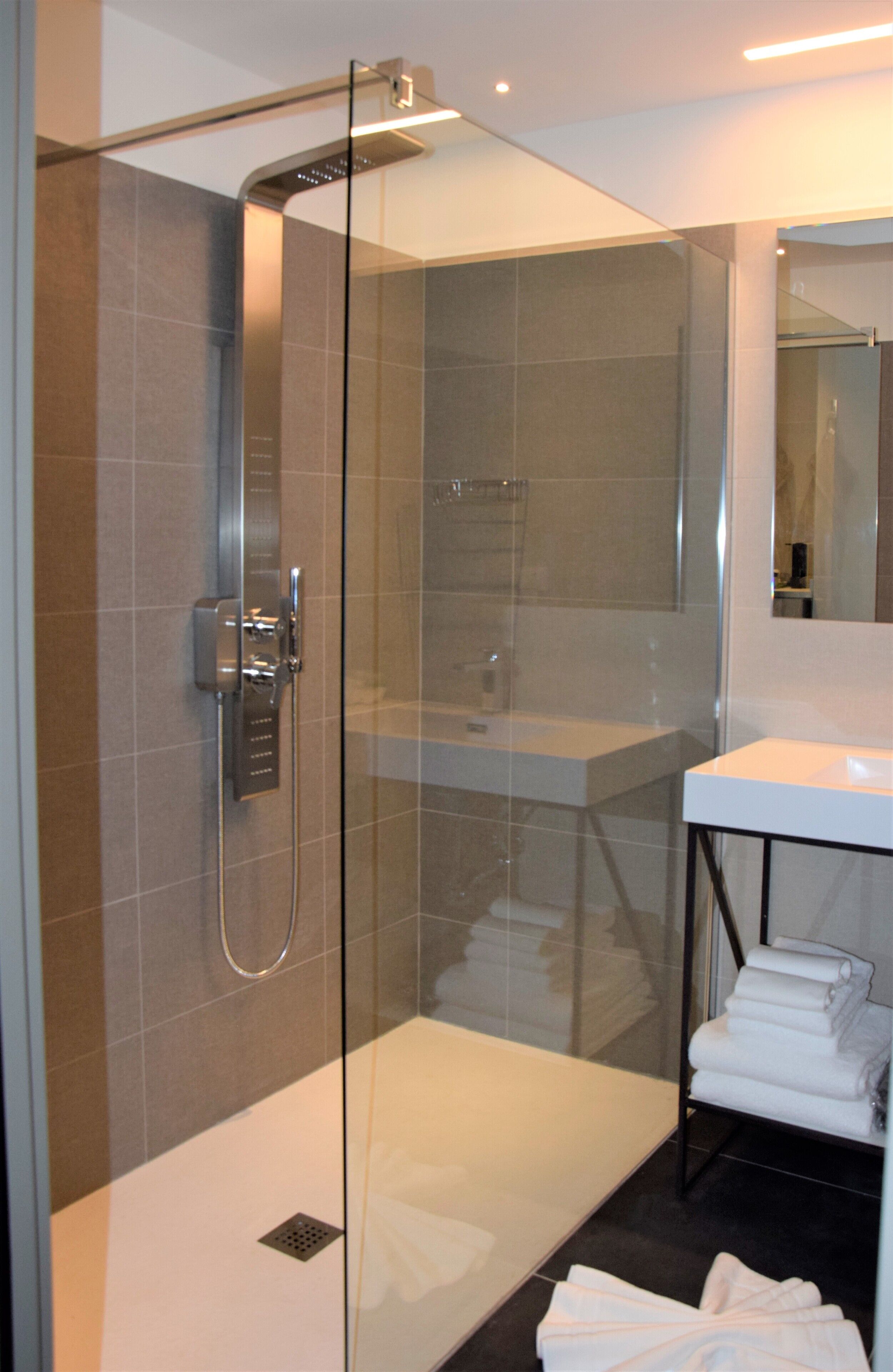 Une salle de bain moderne avec une douche à parois de verre, un lavabo blanc et un porte-serviettes.