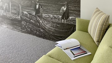 A room with a green sofa, a magazine, and a large black and white landscape painting.