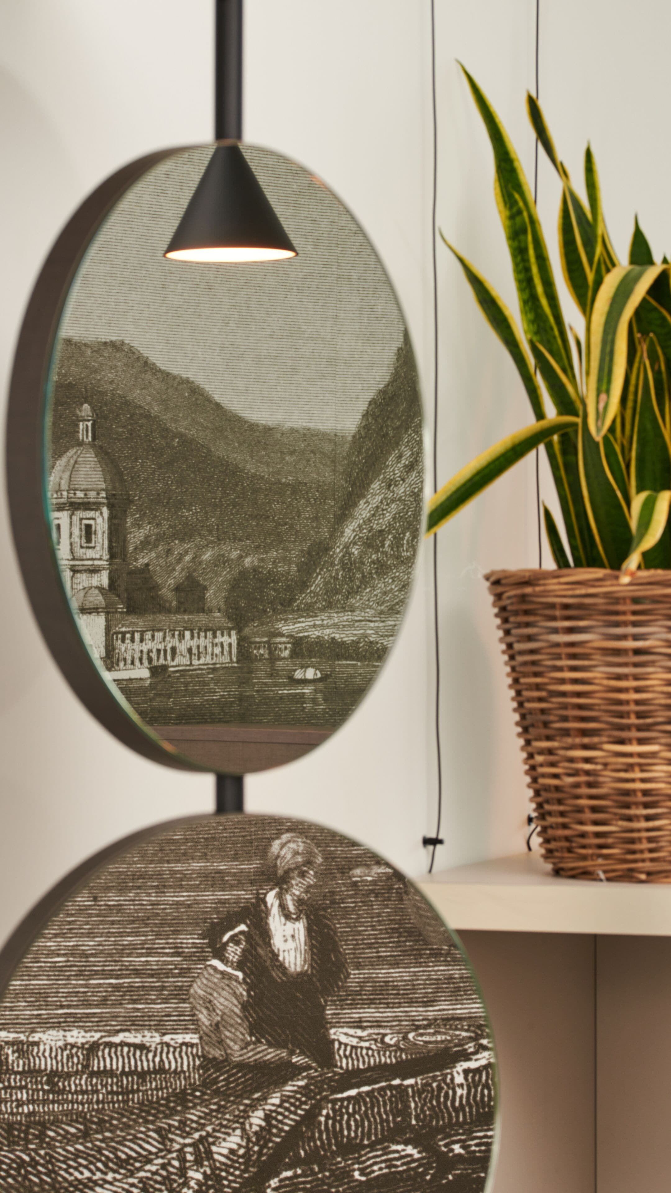 A round mirror with a black frame, reflecting a detailed drawing of a person reading a book.