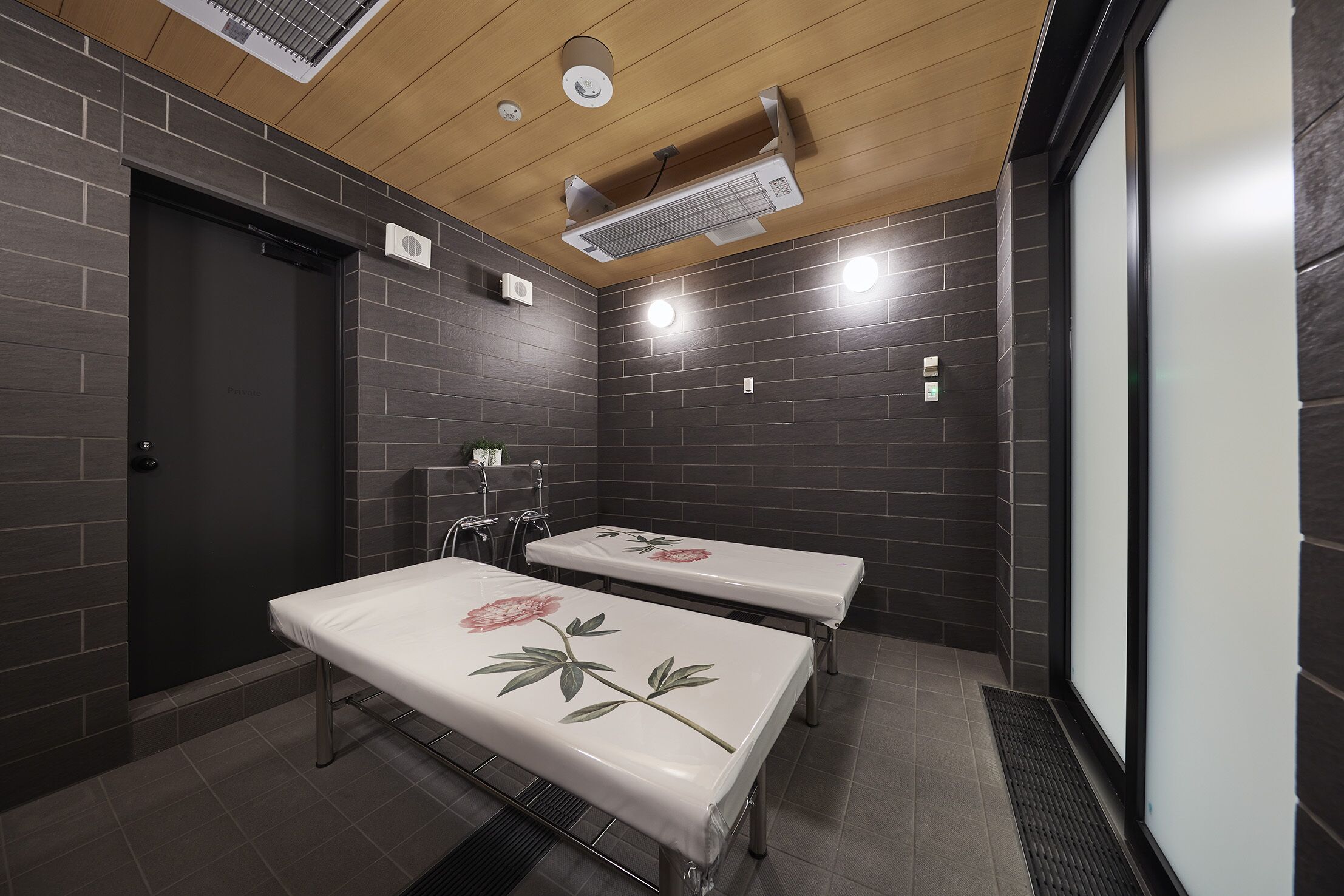 A modern bathroom with two benches, a wooden ceiling, and a ventilation system.