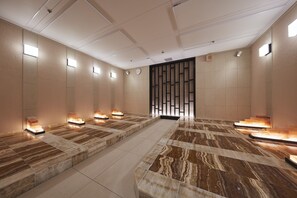 A modern hotel lobby with marble flooring, recessed lighting, and a large reception desk.