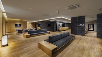 Eine moderne Lobby mit Holzböden, einem Empfangsbereich, Sitzgelegenheiten und einem Spa-Bereich.
