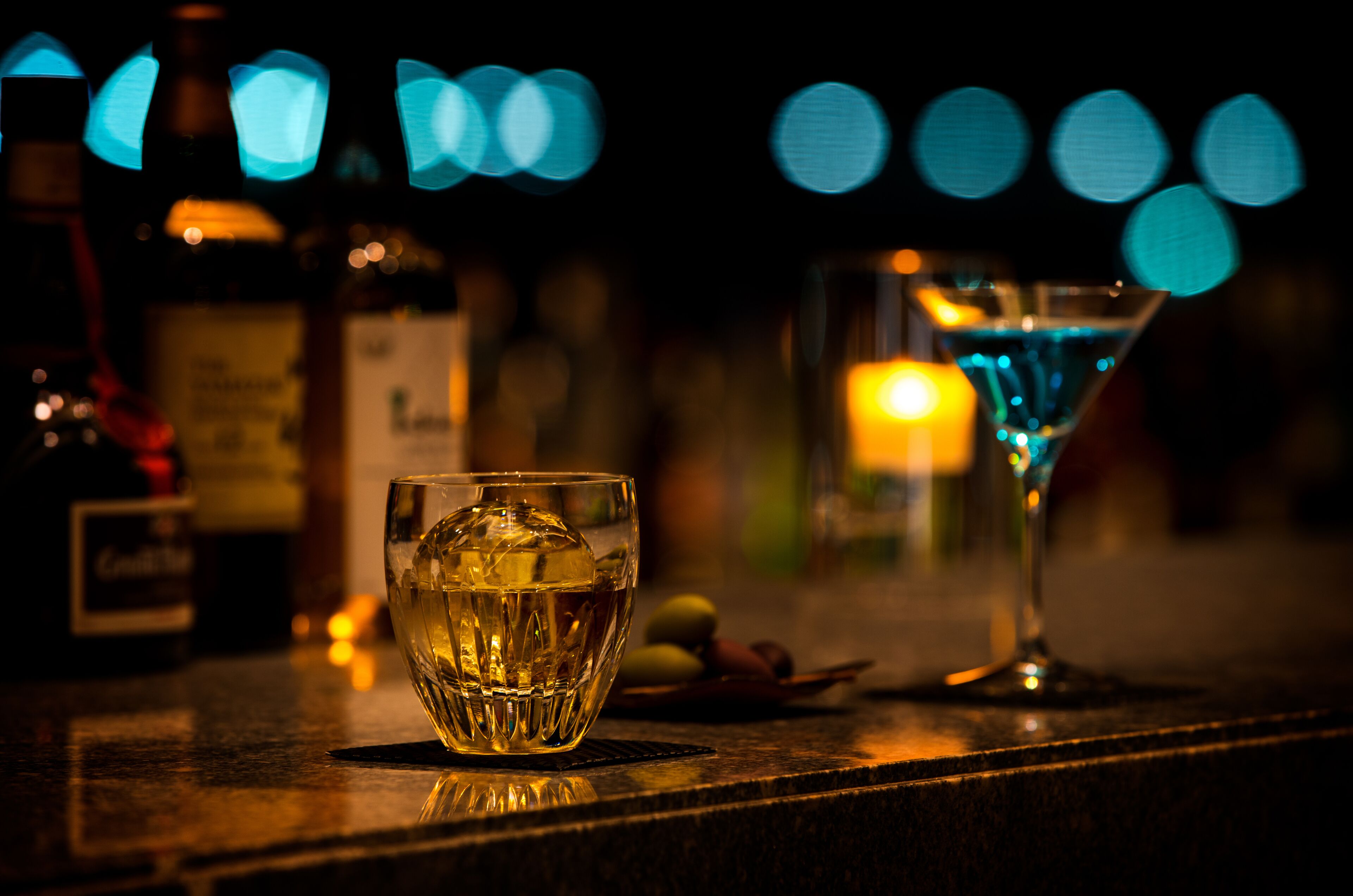 A bar setting with a glass of whiskey and a martini glass.