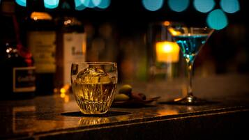 A bar setting with a glass of whiskey and a martini glass.