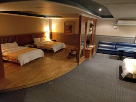 Habitación de hotel con dos camas, zona de estar y un ventanal grande.