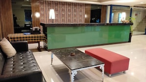 A reception area with a green counter, a black leather sofa, a red bench, and a patterned wall.