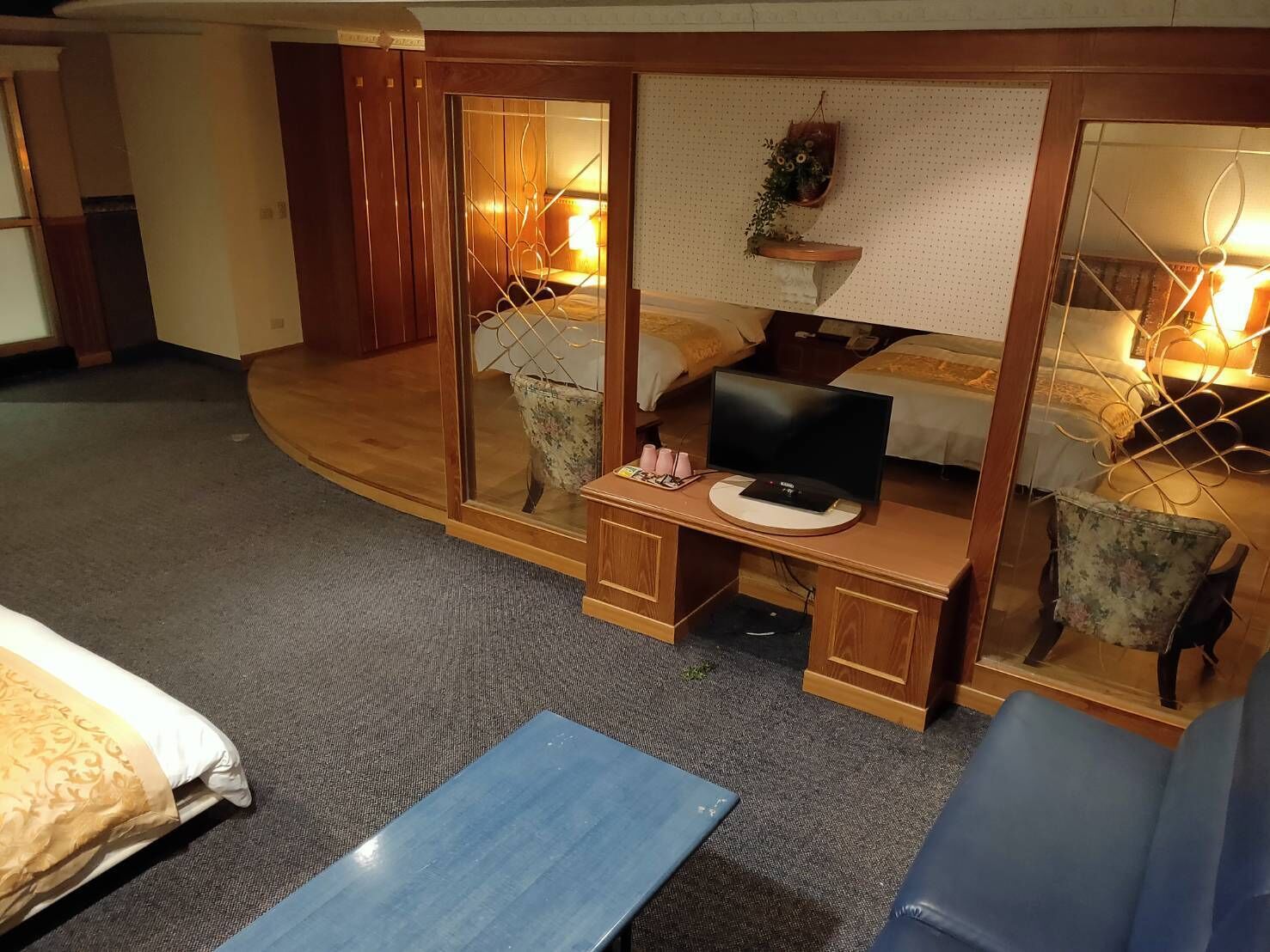 Habitación de hotel con cama, escritorio con computadora, una silla y una mesita de noche con lámpara.