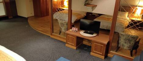 Habitación de hotel con cama, escritorio con computadora, una silla y una mesita de noche con lámpara.