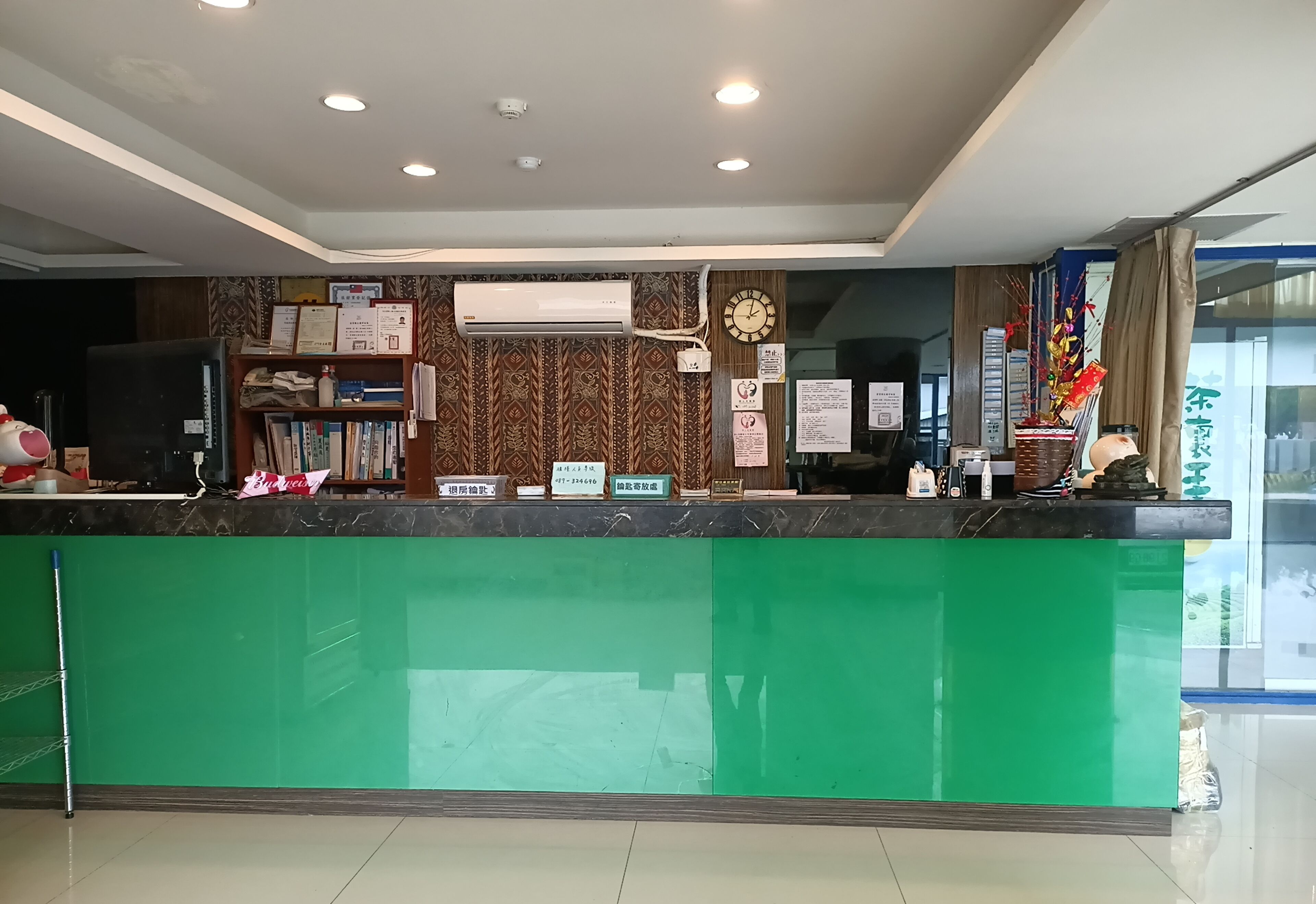 A reception desk with a green counter, a clock, and various informational signs.