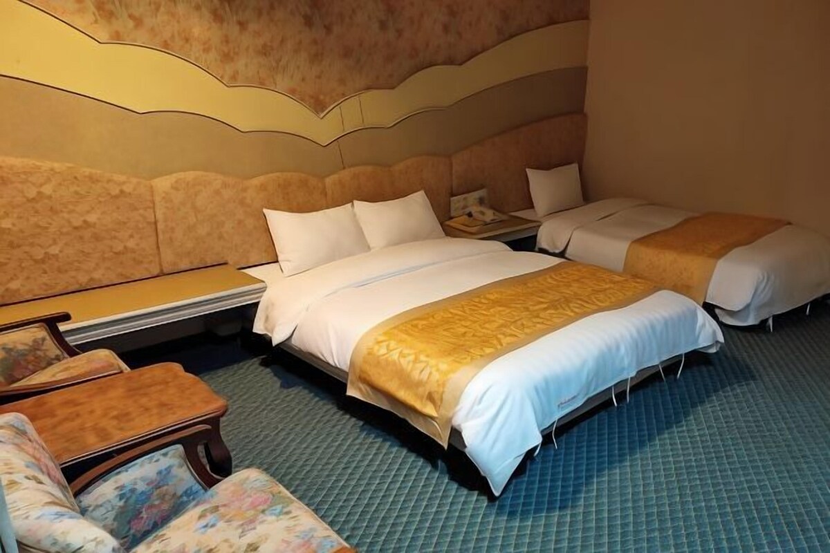 Quarto de hotel com duas camas, um sofá e uma pequena mesa.