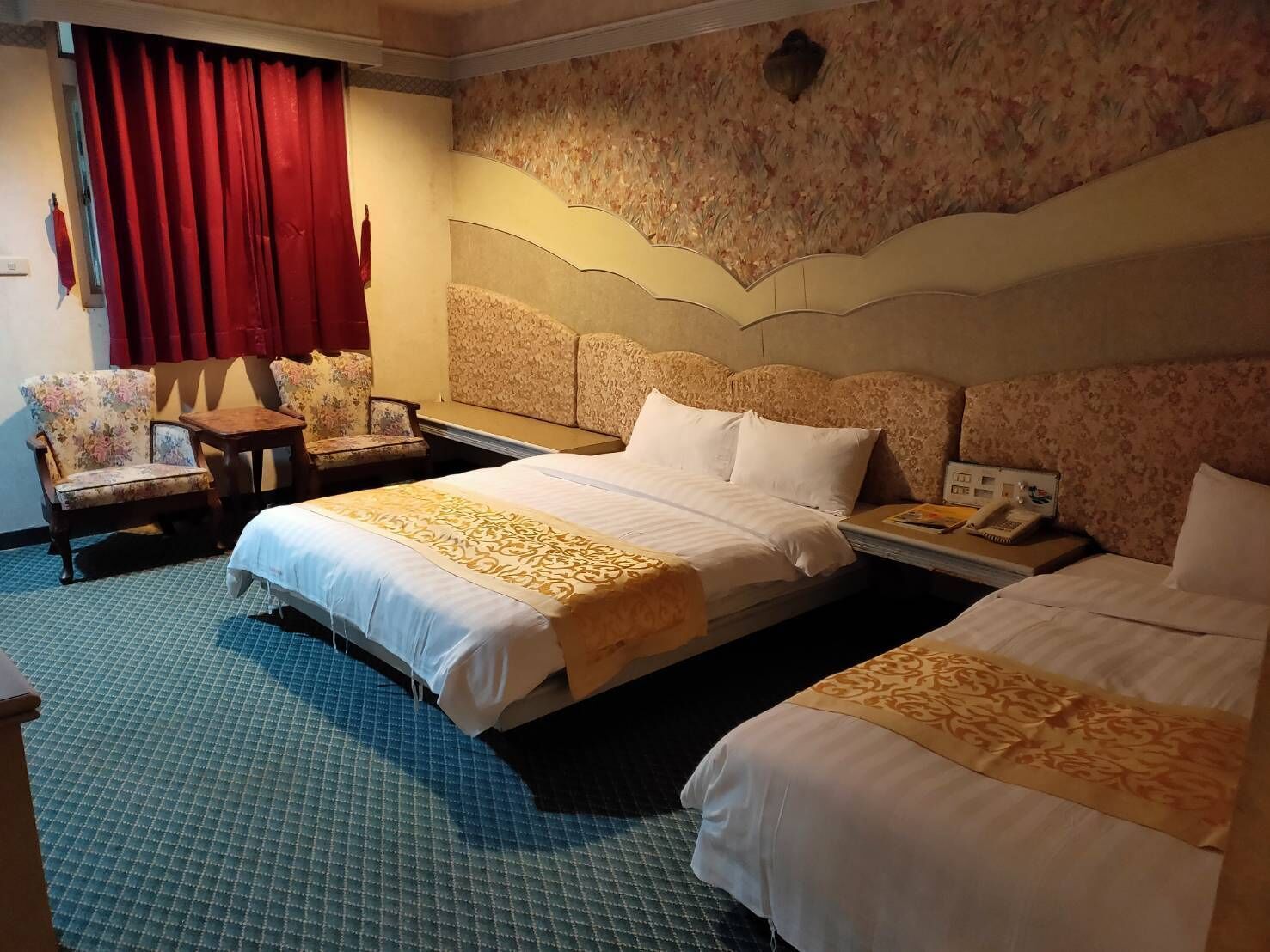 A hotel room with two beds, a desk, a chair, and a telephone.