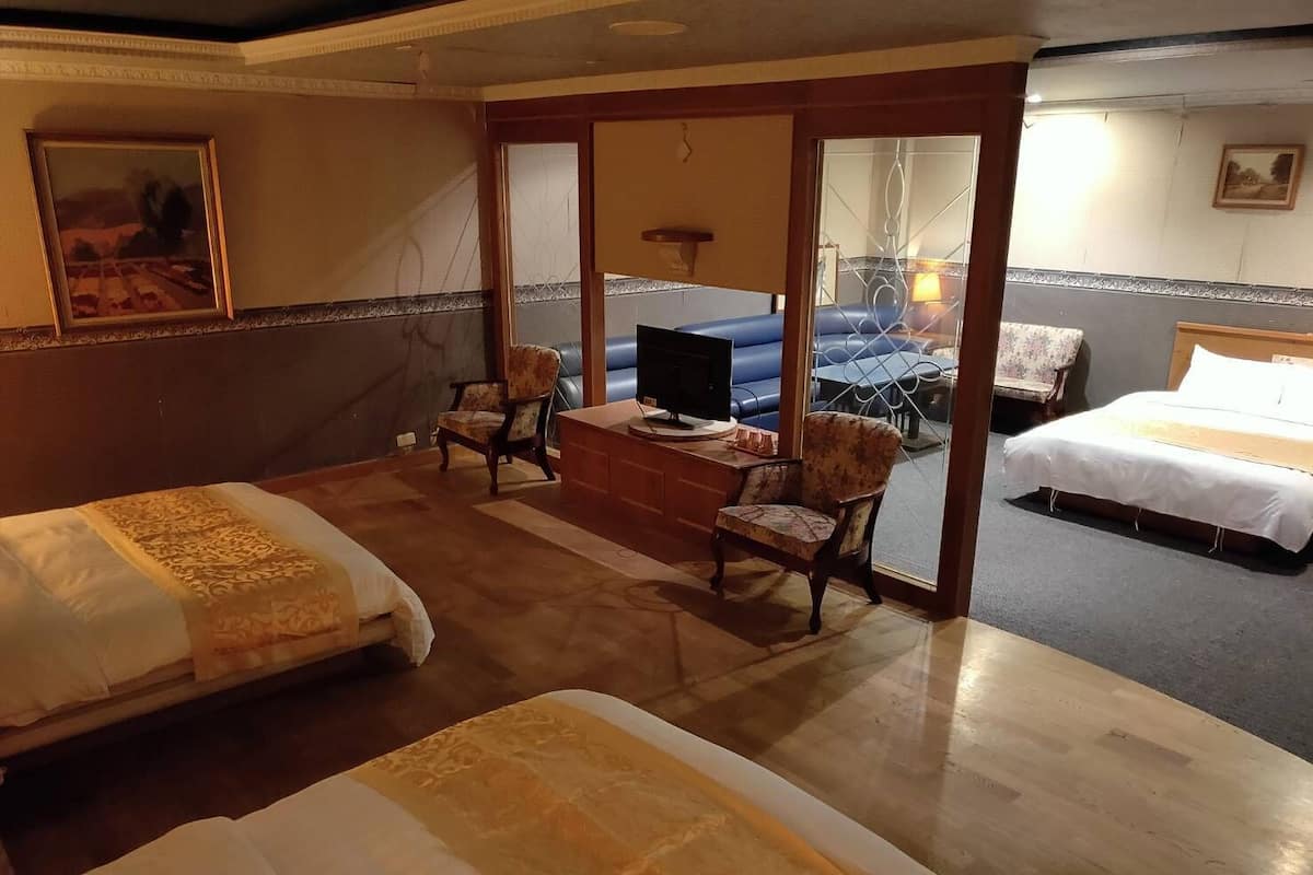 Habitació d'hotel amb dos llits, un escriptori amb televisió i una zona de seients amb cadires.