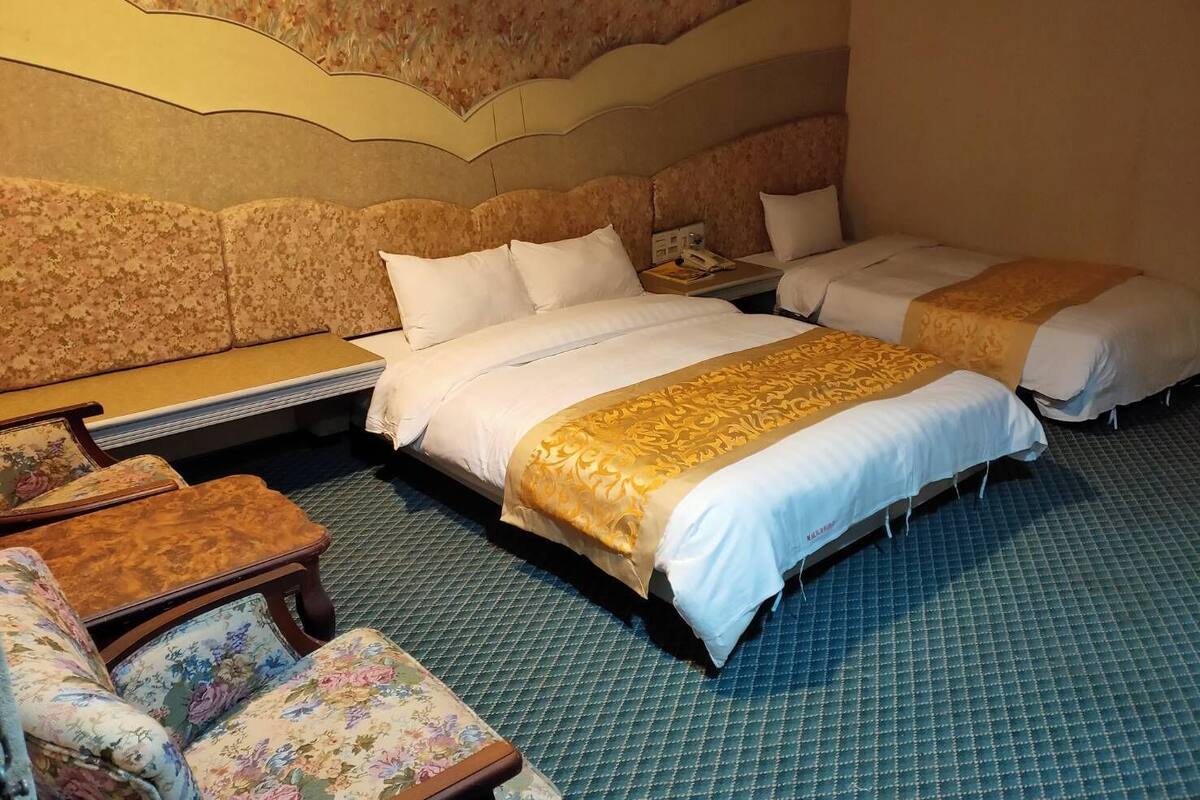 Habitació d'hotel amb dos llits, un sofà, una taula petita i un mur amb dibuixos.