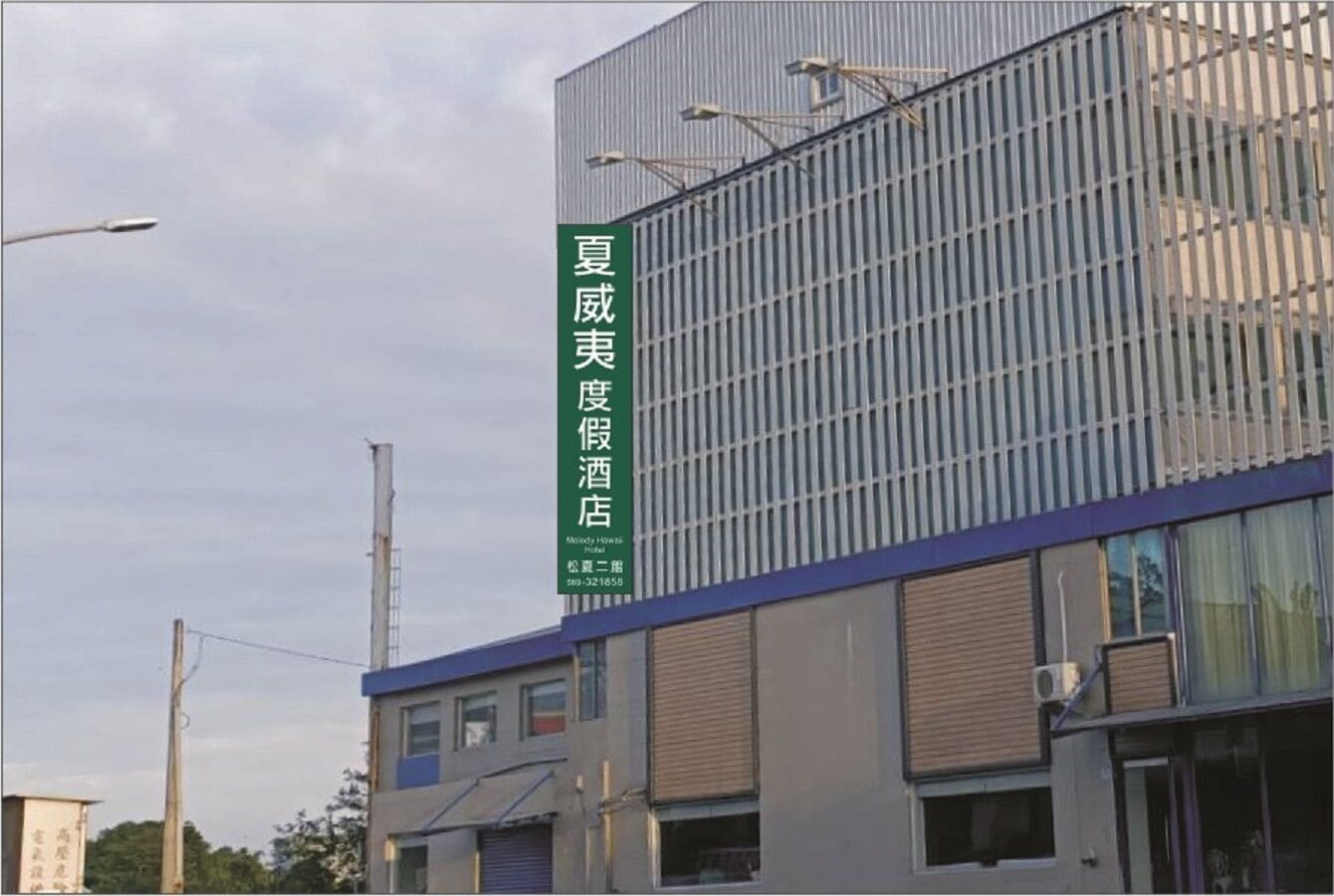 Un edificio moderno con un letrero vertical que indica un hotel.