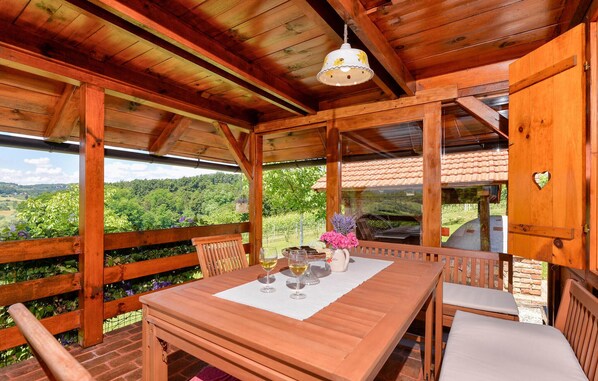 A wooden cabin with a dining area, a table with chairs, and a hanging light fixture. - Cozy home in Lepoglava with sauna (Lepoglava)