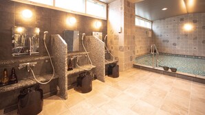 Une salle de bain moderne dotée de plusieurs douches, d’un grand miroir et d’un espace piscine.